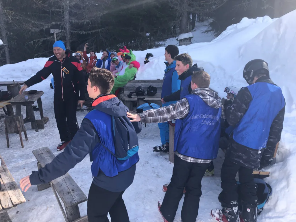 Jugendliche stehen im Schnee vor der Hütte beisammen.